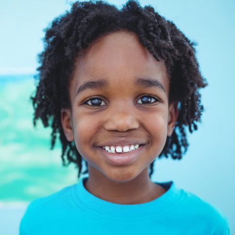 Young boy smiling in front of blue background